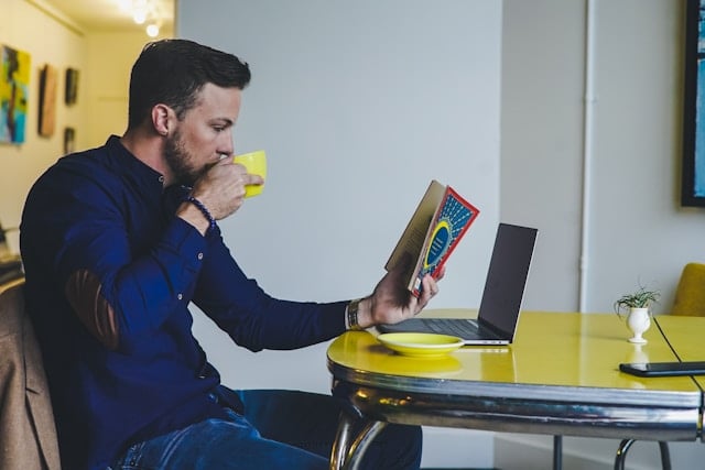Reviewing Andrew Huberman's Supplement Routine in 2025 8 Man reading a book sipping his morning coffee