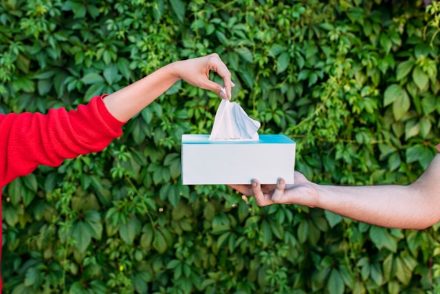 NAD: A New Cure for Seasonal Allergies? 5 A person in a red sleeve pulls a tissue from a white tissue box against green foliage background.