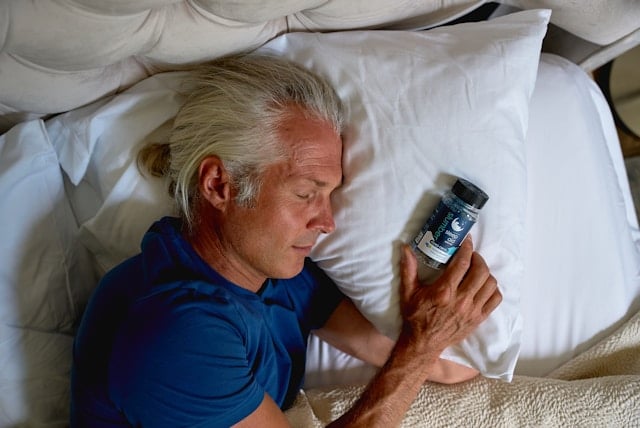Reviewing Andrew Huberman's Supplement Routine in 2025 7 Middle aged man sleeping in bed next to a sleep aid supplement