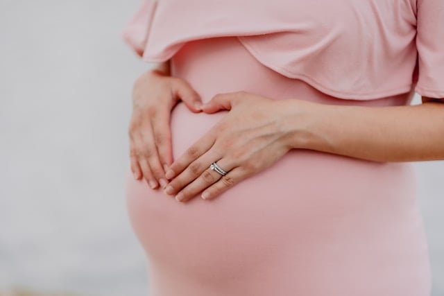 Should Women Take NAD+ Supplements? 7 A pregnant woman in a pink dress holds her belly in a heart shape
