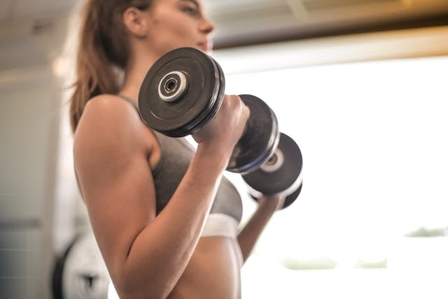 Why NAD+ Matters for Bodybuilding and Muscle Growth 4 A woman bodybuilder in the gym doing dumbbell bicep curls