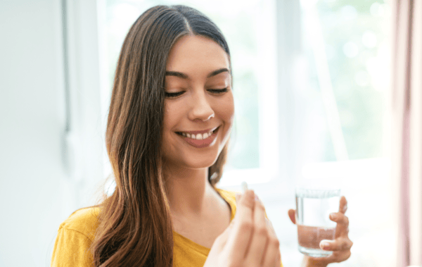 Choosing a High Quality Turmeric Supplement: Buyer's Guide 8 a woman holding a pill and a glass of water