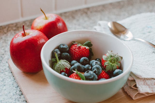 Quercetin vs. Fisetin: Differences and Combined Benefits 4 Bowl of Strawberries and Berries next to Apples on Chopping Board