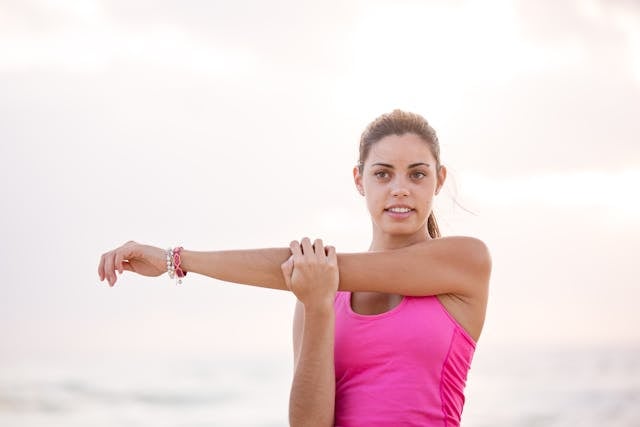 Chronic Fatigue Supplements: What Science Actually Says 8 Woman in pink tank top stretching arm outdoors at sunset