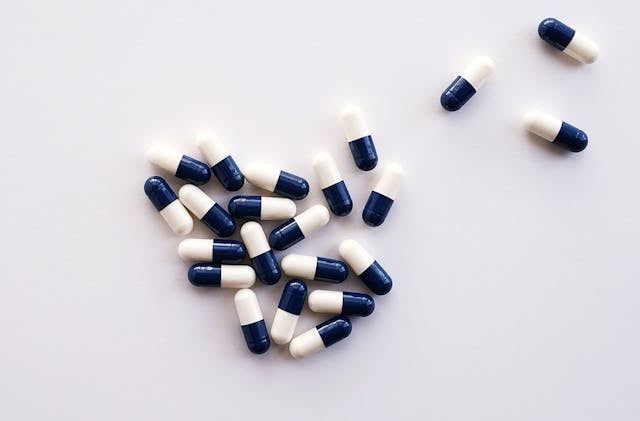 NMN for Brain Fog: Exploring its Role in Cognitive Function 7 Multiple supplement capsules scattered on a white surface.
