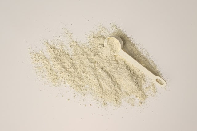 Top 17 Forms of Vitamin C in Supplements (Reviewed) 4 White supplement powder on a light beige table with a scoop