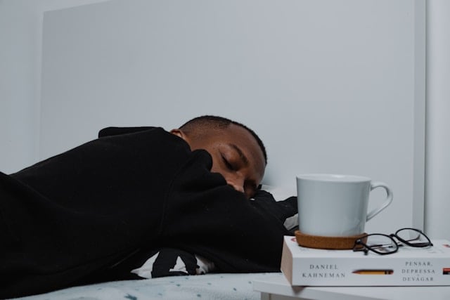 Does Creatine Help Reduce Sleep Deprivation? 4 A man falling asleep next to a cup of coffee
