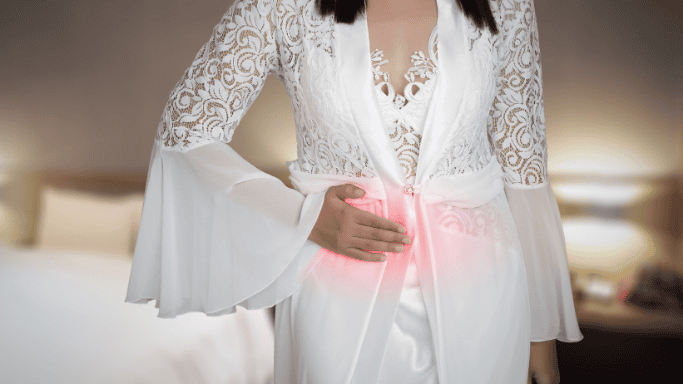 5 Anti-Inflammatory Health Benefits of Ginger Root 13 A woman in a white dress holding her inflamed stomach, appearing to be in pain.