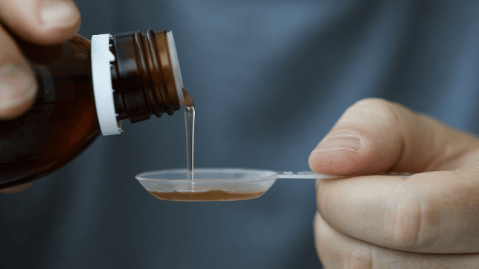Can Vitamin C and Zinc Prevent or Shorten Your Cold? 7 An image of a close-up of liquid medicine being carefully poured from a bottle into a measuring spoon.