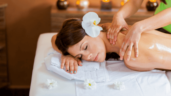 A woman lying face down on a massage table, receiving a relaxing back massage.
