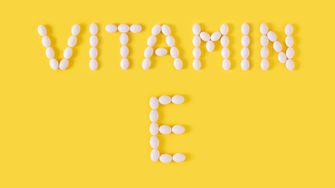 10 Vitamins and Minerals with Anti-Aging Benefits 9 An image showing Vitamin E supplements arranged creatively, spelling out 'VITAMIN E'.