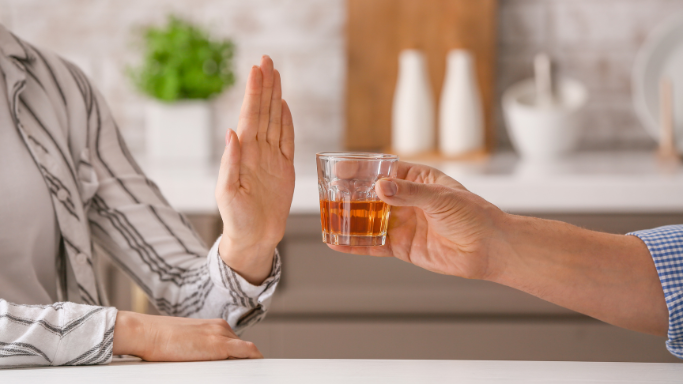 Niacin (B3): Side Effects, Reactions, Overdose Risks Explained 7 an image showing a person politely refusing an offer of alcohol, using a hand gesture to signal refusal.
