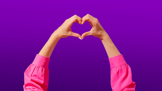 Niacin (B3): Side Effects, Reactions, Overdose Risks Explained 6 An image showing two hands forming a heart shape against a purple background, with the person wearing a bright pink long-sleeve shirt.