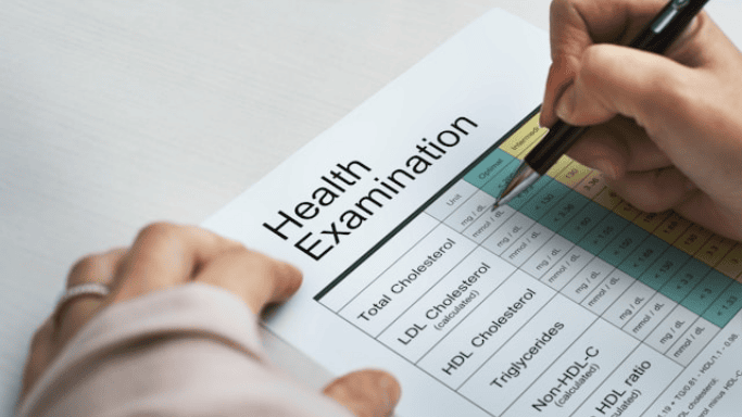 Is Niacin Good for Your Heart? New Studies Show Hidden Risks 7 A person fills out a health examination form with a pen, showing cholesterol test results and data.