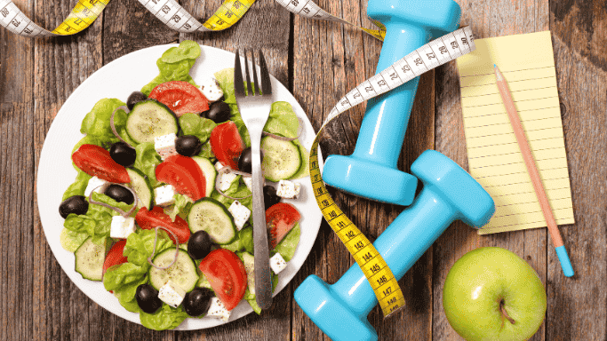 Can Vitamin C Help You Lose Weight? 6 An image featuring a variety of healthy foods placed alongside a dumbbell and a measuring tape, symbolizing a balanced approach to effective weight loss.