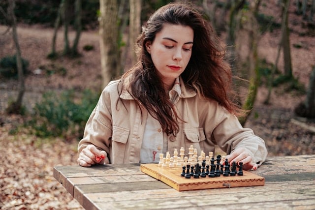 A woman playing a game of chess at the park.