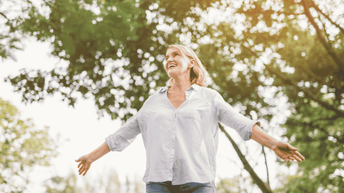 Glutamine vs Creatine: Science-Based Comparison 6 Joyful woman standing outdoors with open arms, symbolizing the recovery, gut health, and immune system benefits of glutamine.