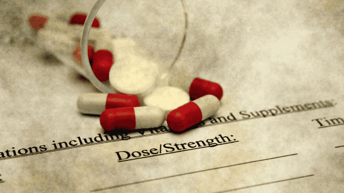 Glutamine vs Creatine: Science-Based Comparison 11 Prescription form labeled 'Dose/Strength' with red and white capsules spilled over it, representing supplement dosage and timing recommendations.