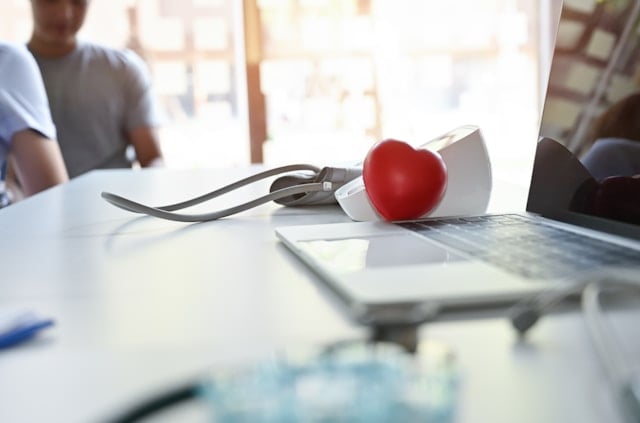 Niacin (B3): Side Effects, Reactions, Overdose Risks Explained 9 A stethoscope and red heart sit on medical papers at a doctor's desk with a blurred person behind.