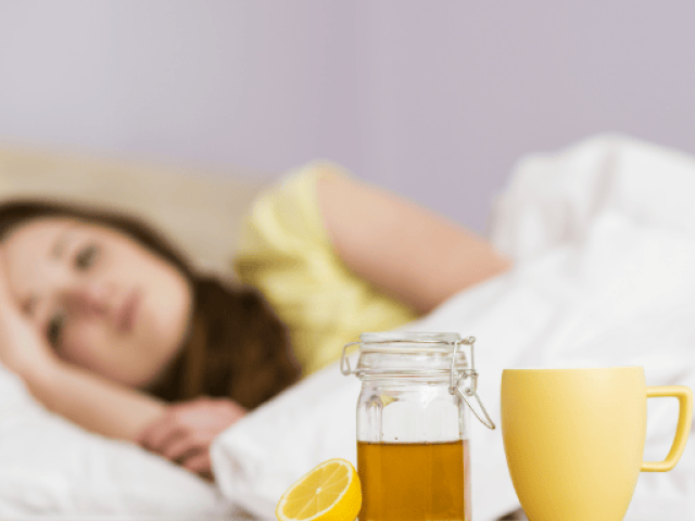 Bryan Johnson Blueprint Supplement List Reviewed (2025) 8 An image showing a sick woman lying in bed with lemon tea on bedside table for cold relief.