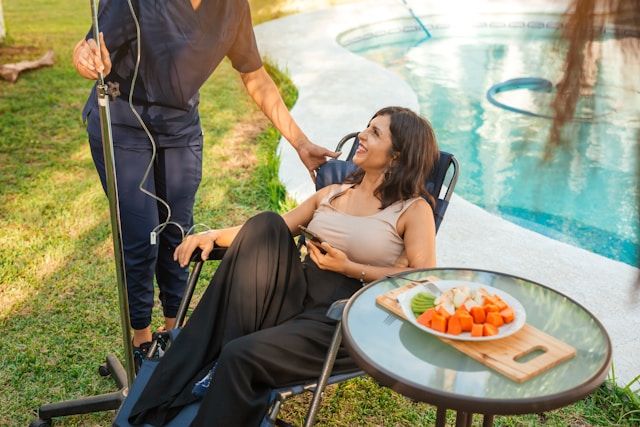 A woman receiving a NAD+ injection drip by the pool at a wellness clinic