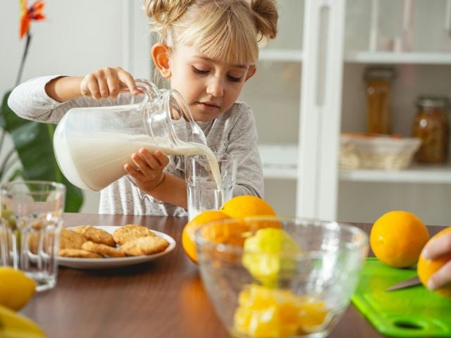 Niacin (B3): Side Effects, Reactions, Overdose Risks Explained 9 A child pours a glass of milk while her mother cuts oranges in the background.