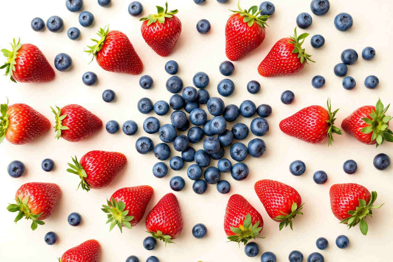 Fresh strawberries and blueberries arranged in a perfect symmetrical pattern on a light background