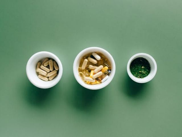 Supplements in small bowls on a green background