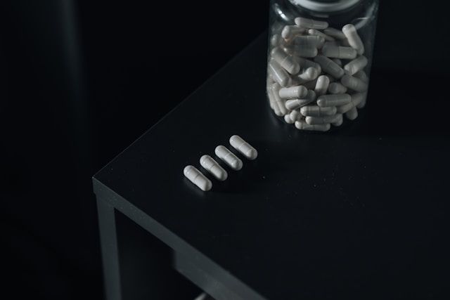 A bottle of supplement capsules on a black table