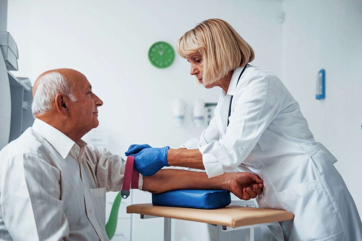 A nurse preparing an older man for a CRP blood test.