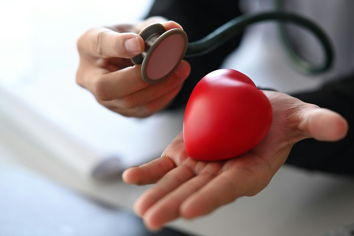 Closeup of doctor's hand holding a model heart and stethoscope