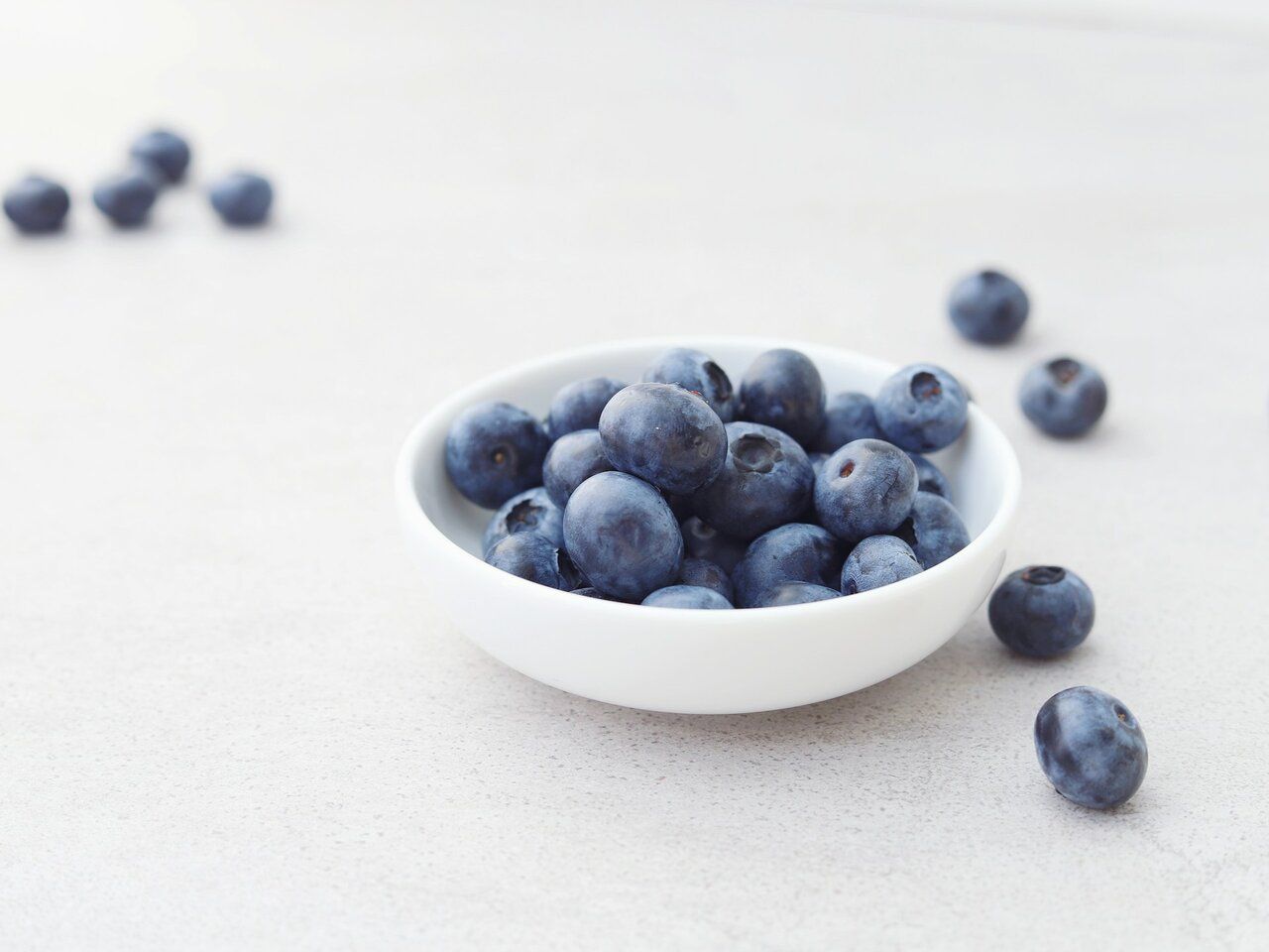 A bowl of blueberries on a white table