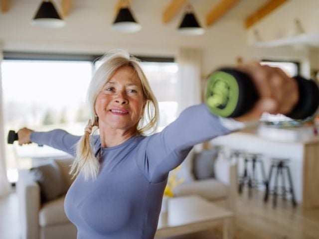Reviewing Dr. David Sinclair's Supplement Regimen in 2025 6 A healthy older woman in a gray top performs arm exercises with dumbbells at home.