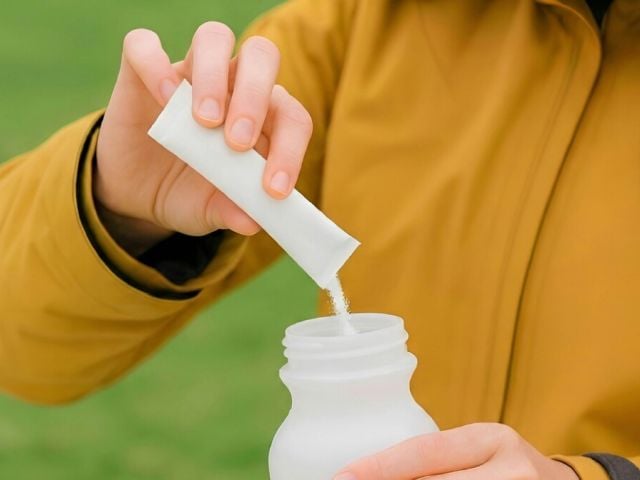 A woman pours magnesium powder into her water bottle