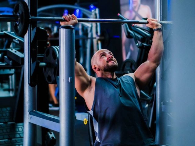 Why Take Quercetin with Bromelain? 7 Health Benefits to Know 10 A man doing shoulder presses in the gym.