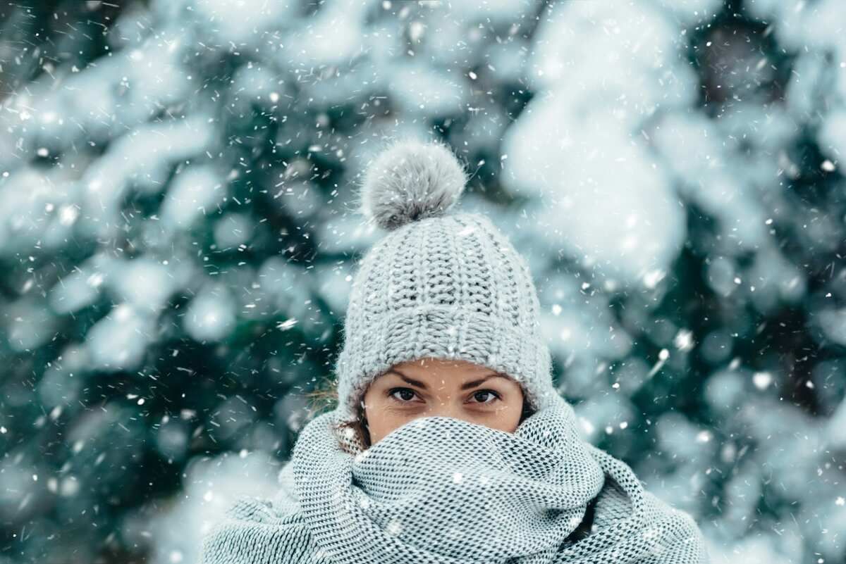 A woman dressed for winter in a white tuque outdoors.