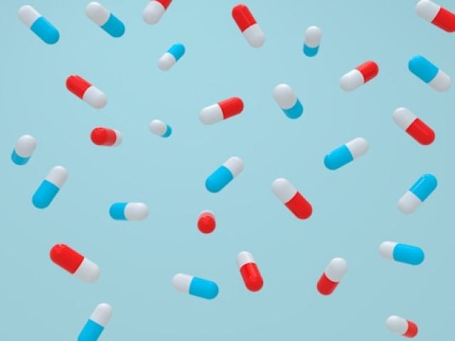 Creatine Starter Guide: Loading, Timing & Beginner Tips 4 Colorful red, blue and white capsule pills are scattered randomly across a light blue background.