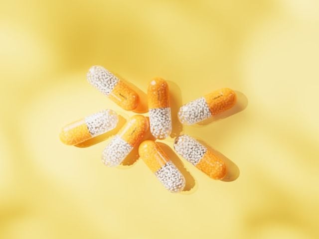 Yellow vitamin C capsules against a soft yellow background.