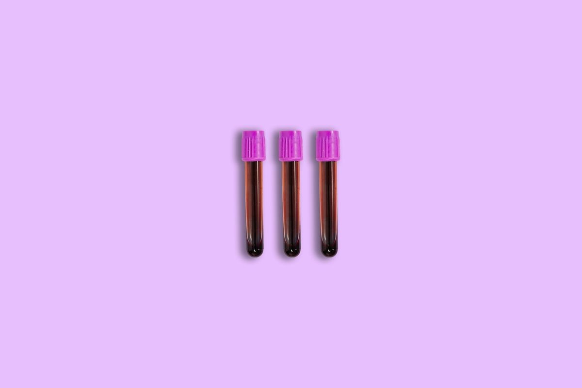Three blood test vials against a purple background.