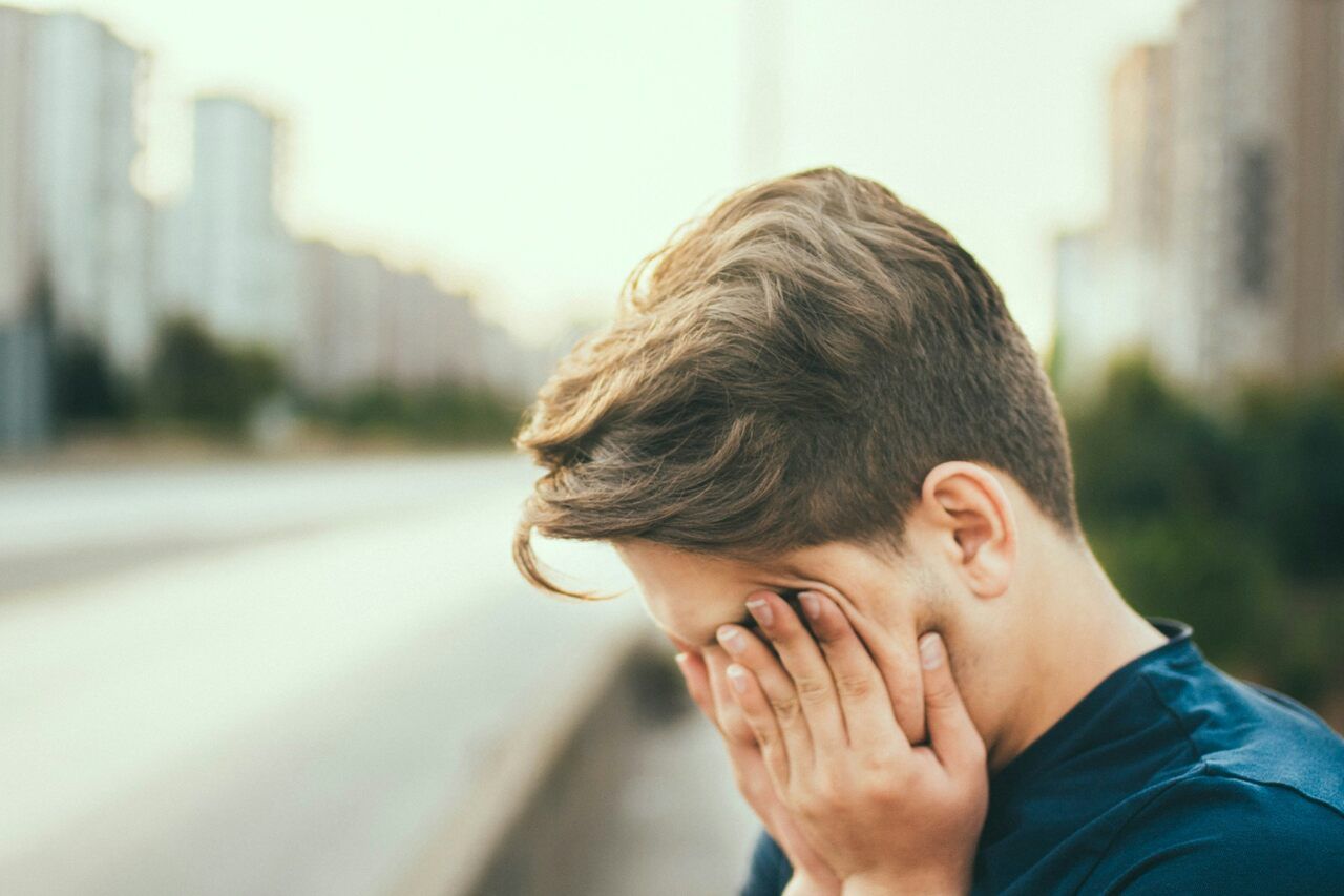 A man with chronic fatigue holds his face in exasperation