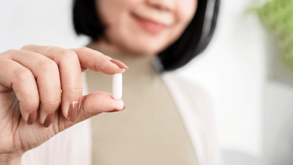 An image of a capsule with a blurry woman in the background