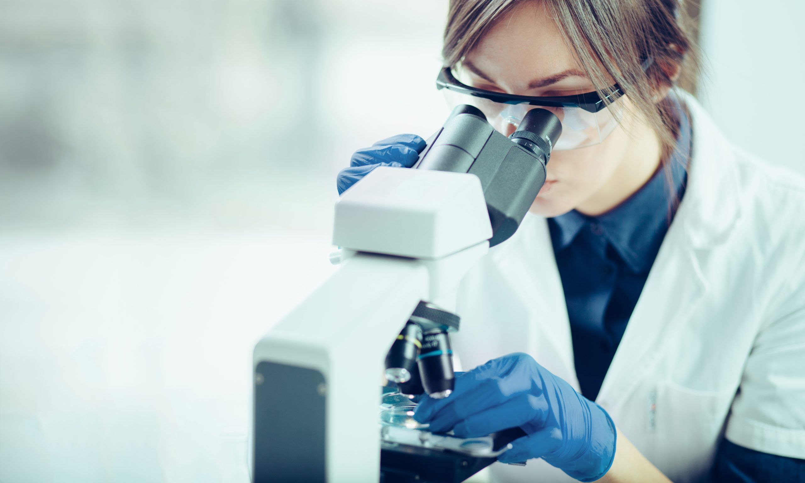 A lab technician woman looking at samples in a microscope