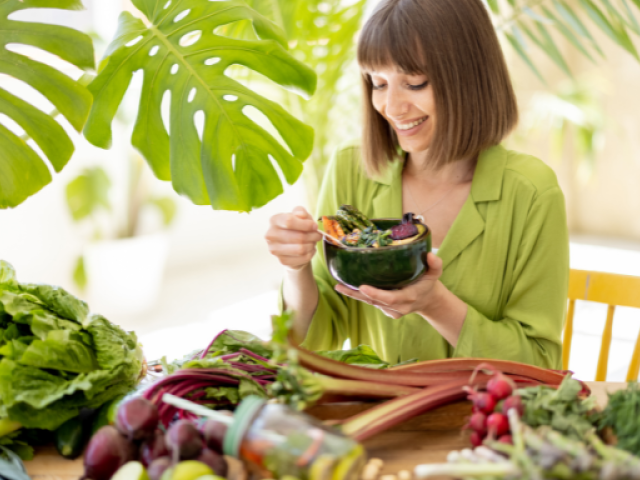 Why Take Quercetin with Bromelain? 7 Health Benefits to Know 10 An image of a Woman enjoying a bowl of vegetables surrounded by fresh, leafy greens, boosting her glutathione levels naturally.