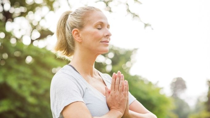 An older woman in a yoga pose outside