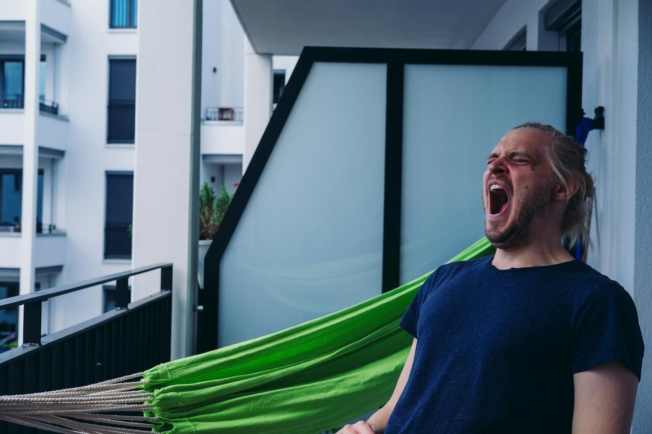 A man yawning on his balcony in the morning