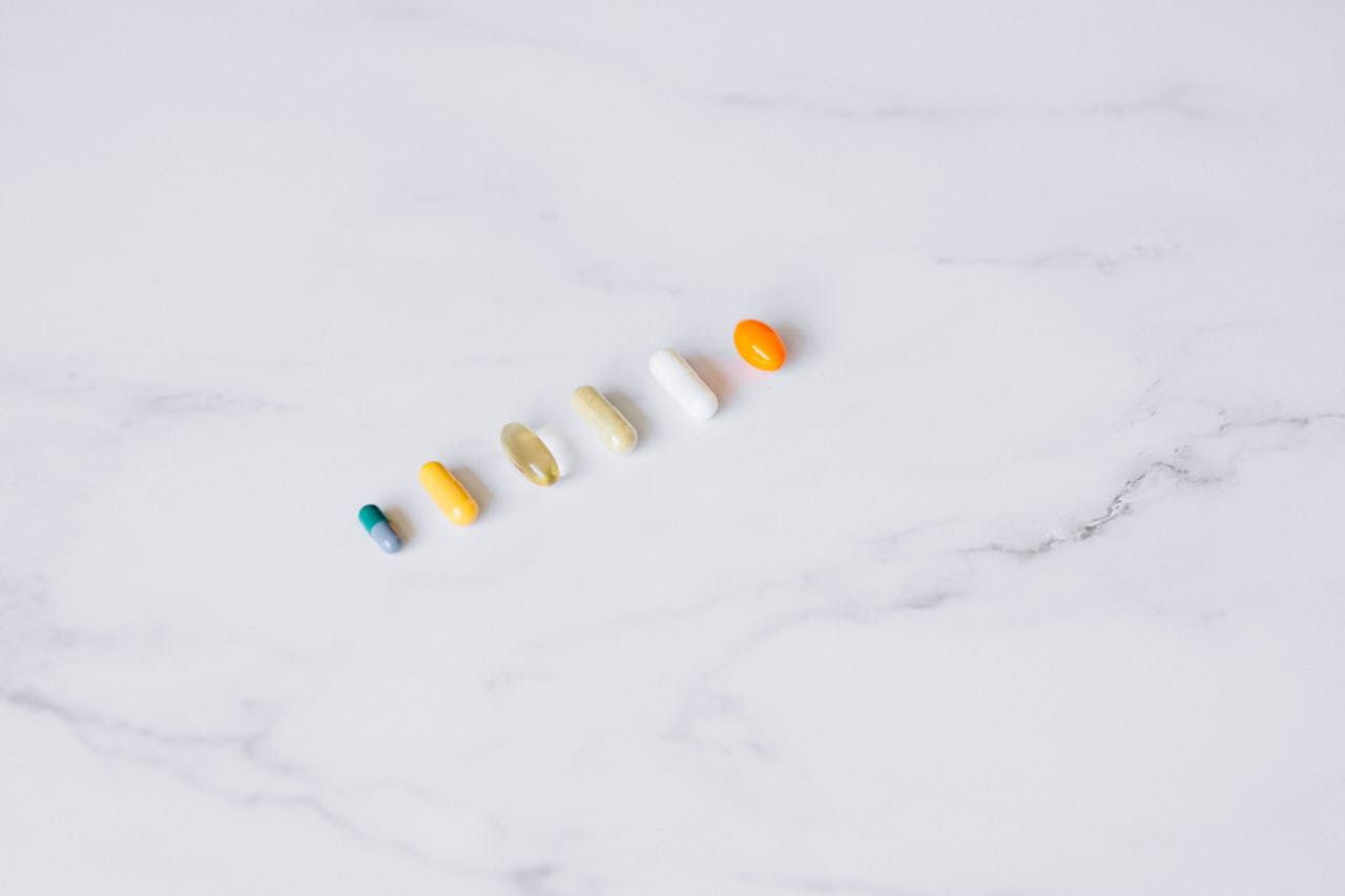 A row of various supplement capsules on a marble countertop