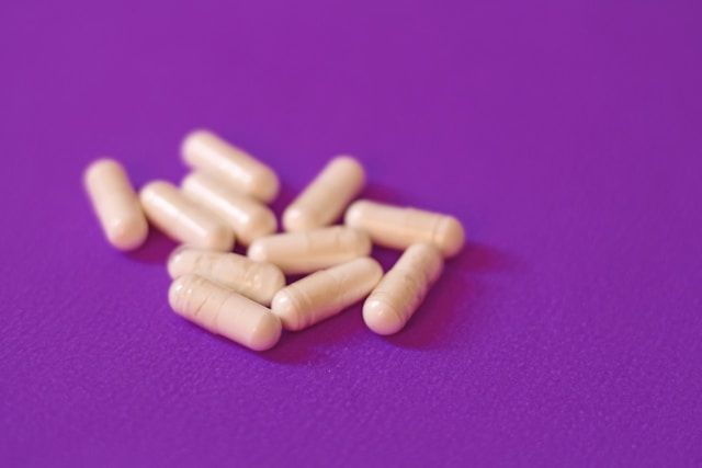 A small pile of supplement capsules scattered on a purple background.