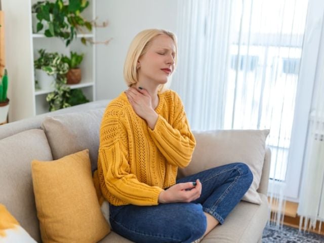 Woman with fibromyalgia neck pain sitting on her couch