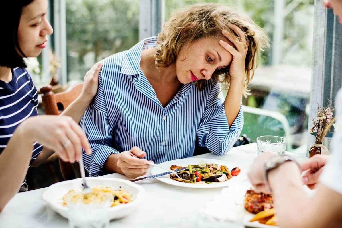 A woman with brain fog after eating holds her head