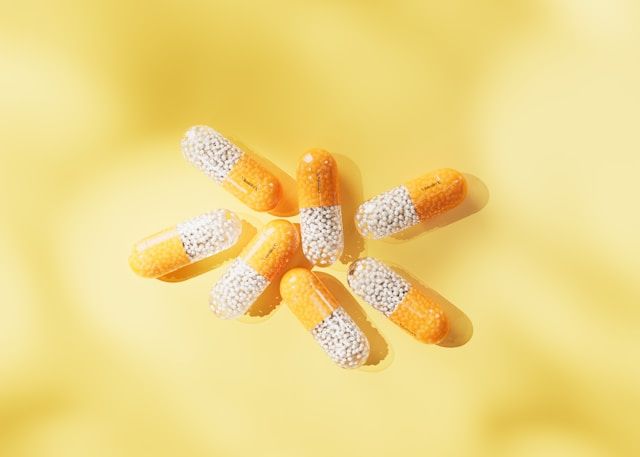 Yellow vitamin C capsules against a soft yellow background.
